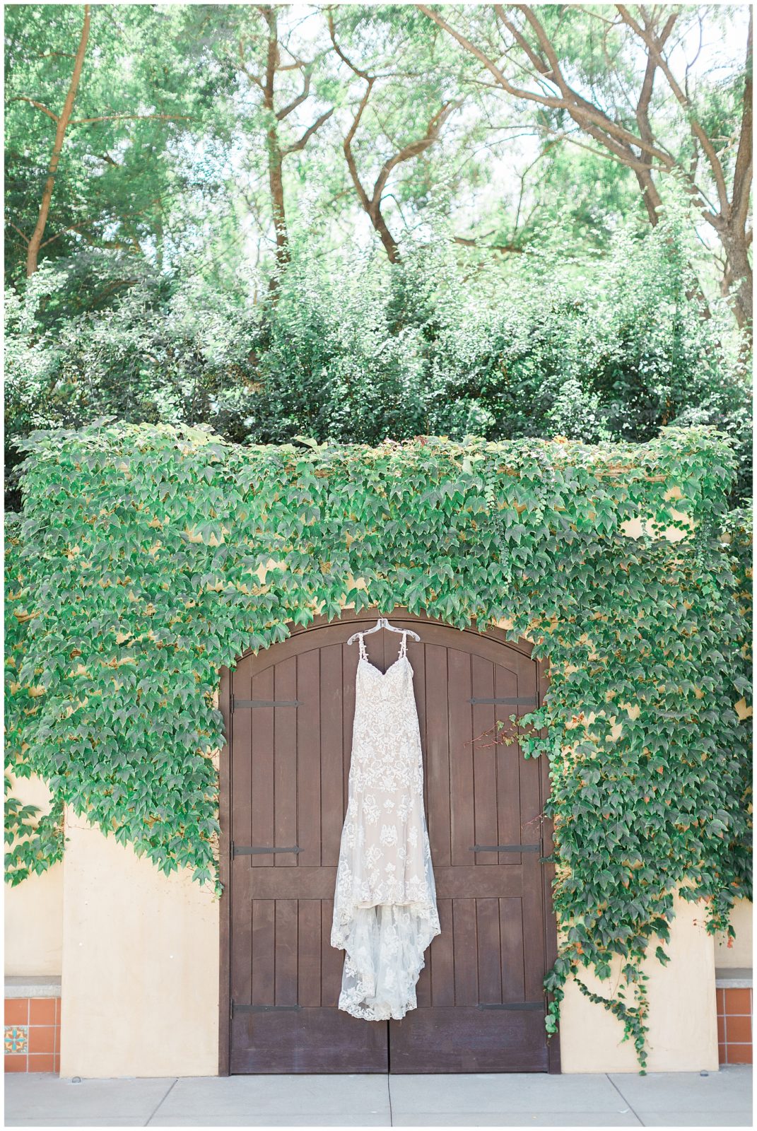 hanging wedding dress outside on greenery