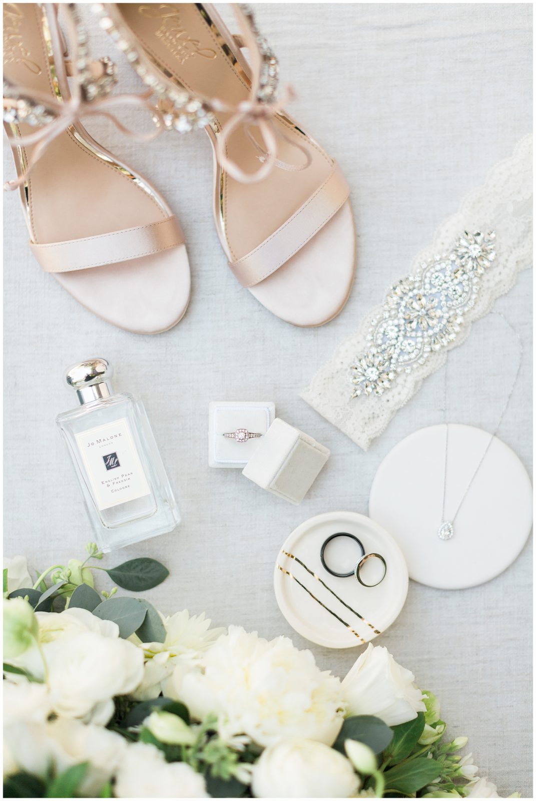 flatlay with shoes, rings, perfume and florals